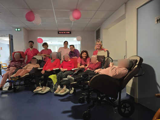 Résidents et soignants en rose à l'intérieur, entourés de ballons