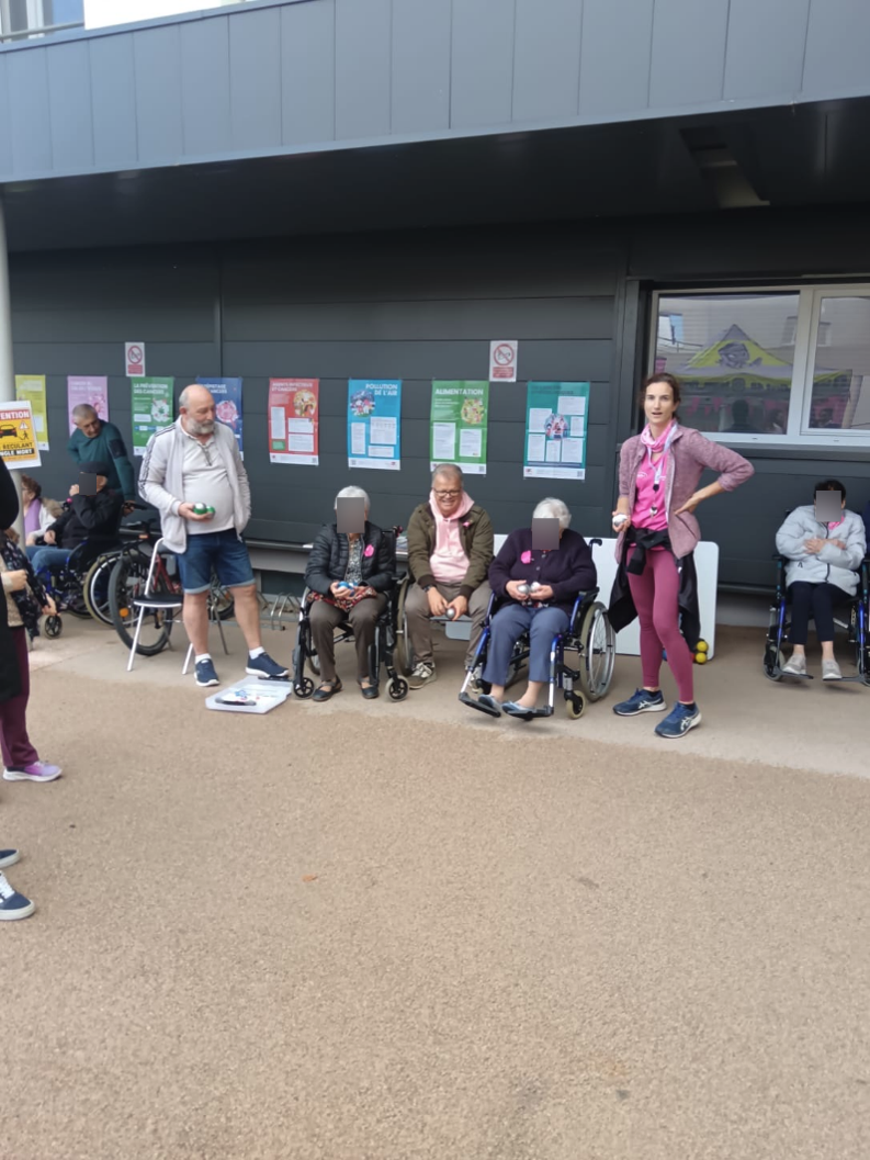Résidents et animatrice lors d'un jeu de boules devant les affiches de prévention